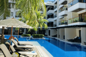 resort hotel with 3 floors, a swimming pool in front and some benches