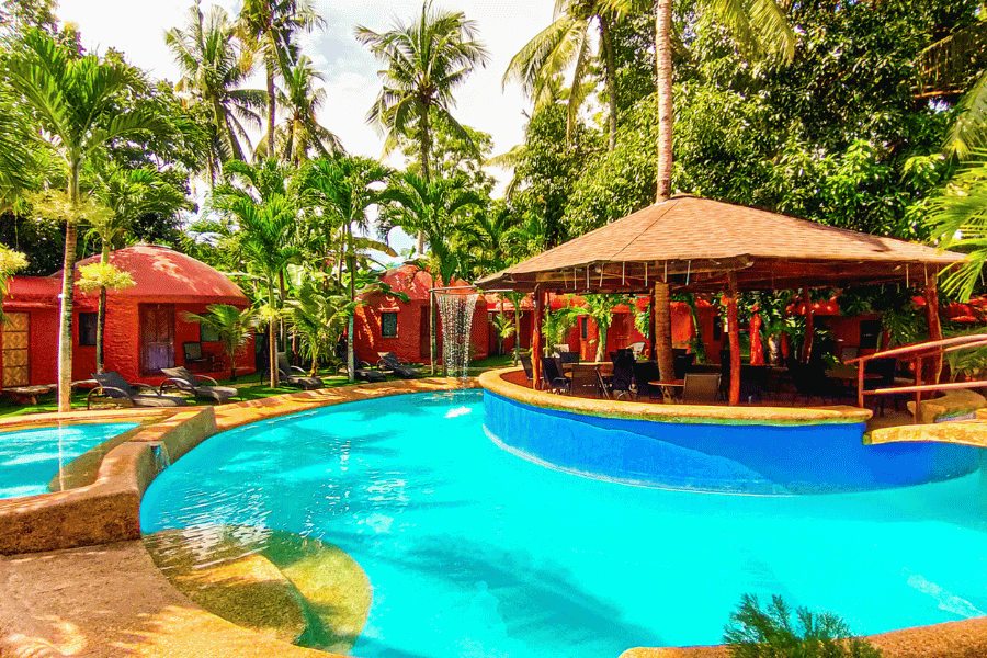 a large swimming pool surrounded by cottages shaped like the chocolate hills