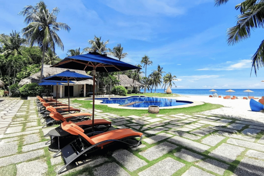 beach lounges with umbrellas, with a view of the infinitypool and the beach under the blue sky