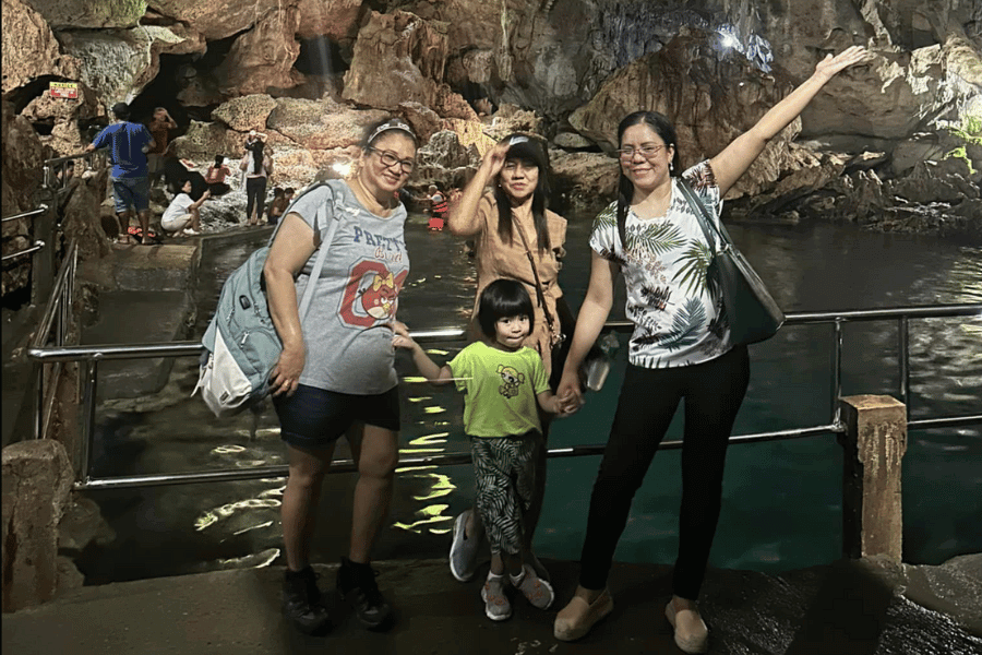 3 women wearing outdoor clothes, and a small girl all inside a cave with the background of a pool of water