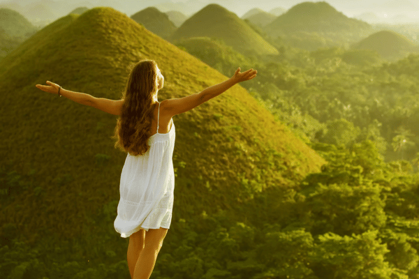 lady in a white dress facing the chocolate hills