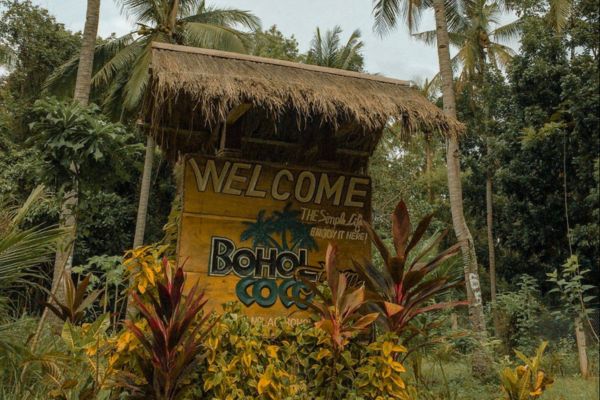 a construct that looks like a make shift nippa hut with a sign that reads welcome to Bohol Coco Farm