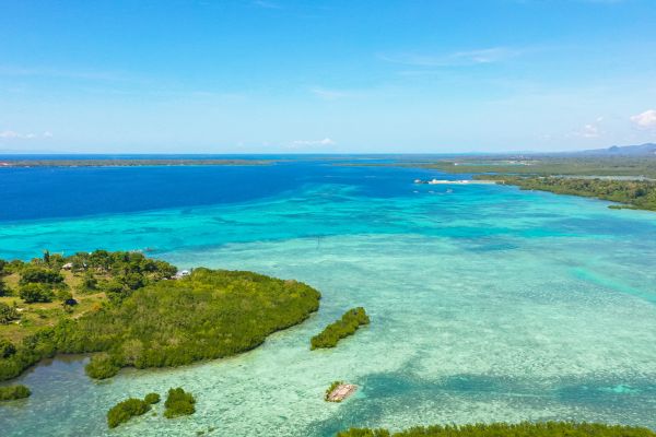turquoise green and blue color in the ocean with some surrounding islands under the clear blue sky