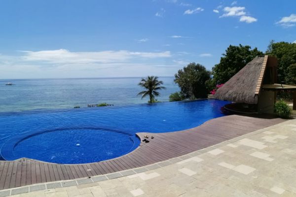 pool deck and the infinity pool with the view of the blue ocean under the clear blue sky