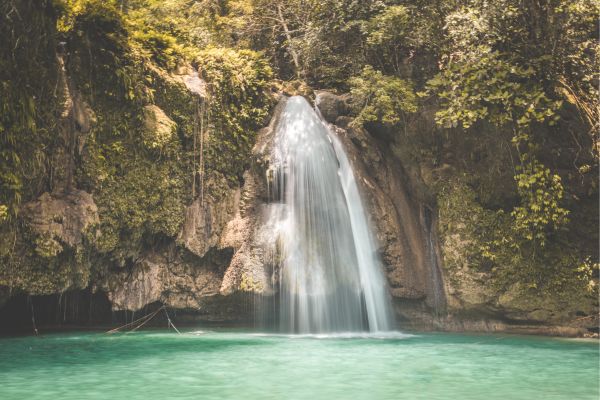 a small falls along the river. the water is blue green in color