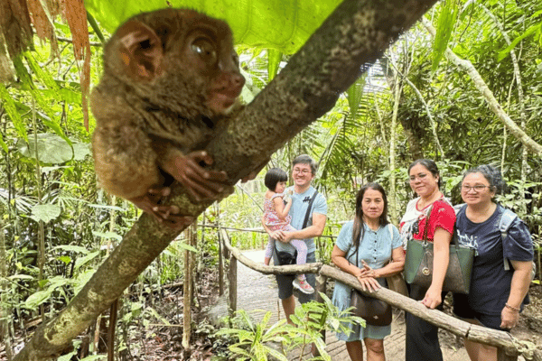 a family picture with 3 women and a man carrying a small girl, with the tarsier as a foreground