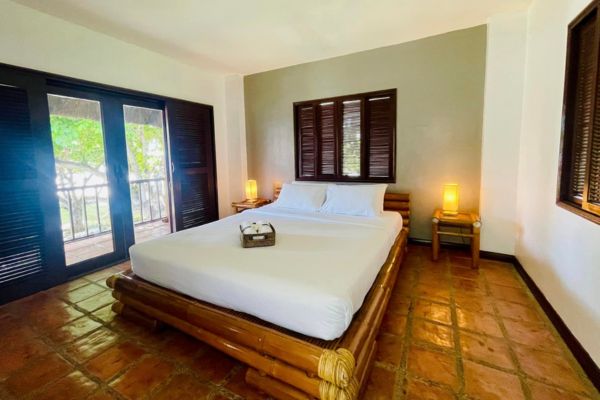a cozy room with a queen size bed with a bed frame that looks to be made of bamboo