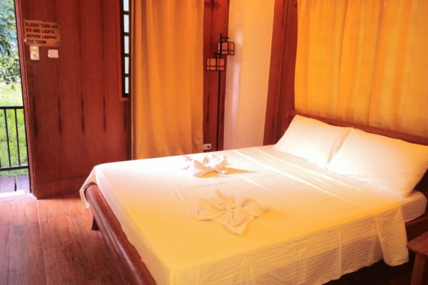 a small room with a double size bed with the walls lined with curtains