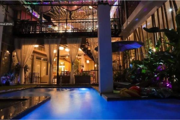 a hotel building at night with the swimming pool in front. surrounded by night lights.