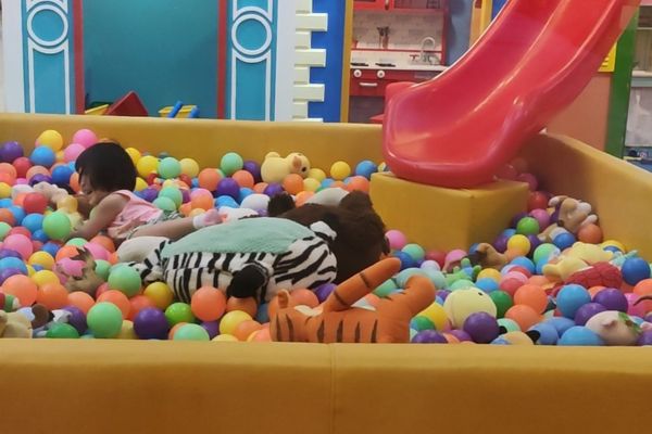 a girl playing inside a ballpit inside a kids playground