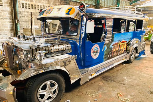 traditional jeepney inn the Philippines with a silver and blue body parked in the street