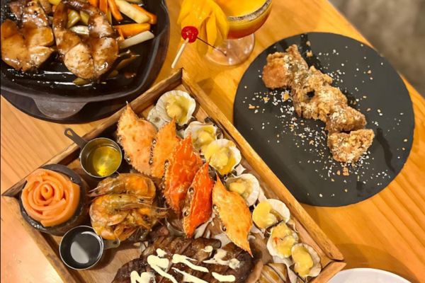 crabs, clams, shrimps, steak with sauce on top, asian fusion chicken on the table