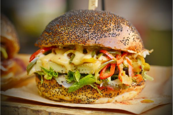 a burger with a toasted sesame bun and lots of vegetables