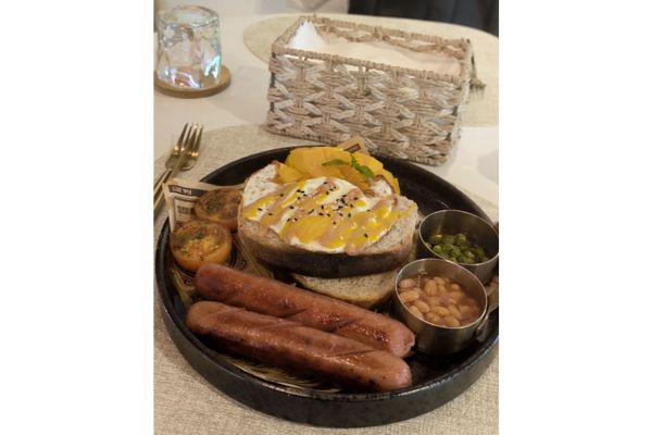 sausage, sourgh dough bread, breans, green peas, tomatoes, egg, and fresh ripe mango on a plate