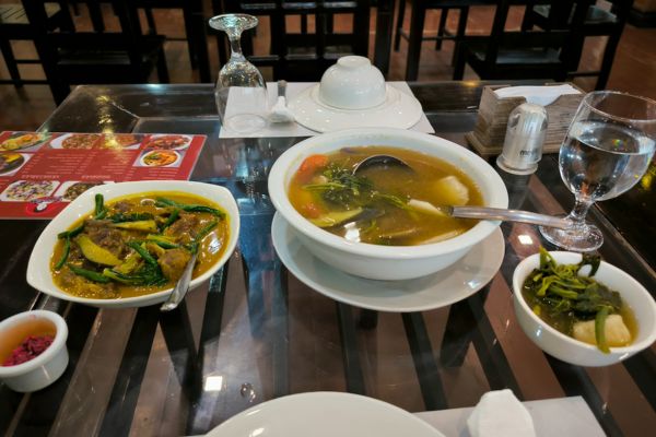 a plate of beef in peanut sauce and salmon fish in sour sauce, a plate of shrimp sauce all neatly placed on a table