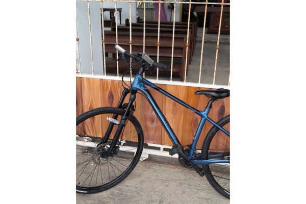 a blue bicycle leaning on a white gate of a chapel