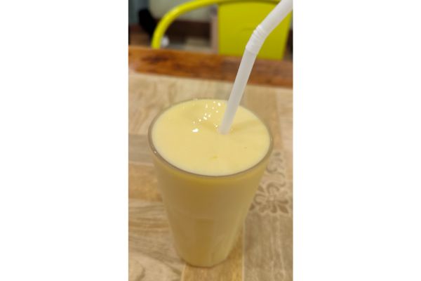 a glass of mango shake with white straw