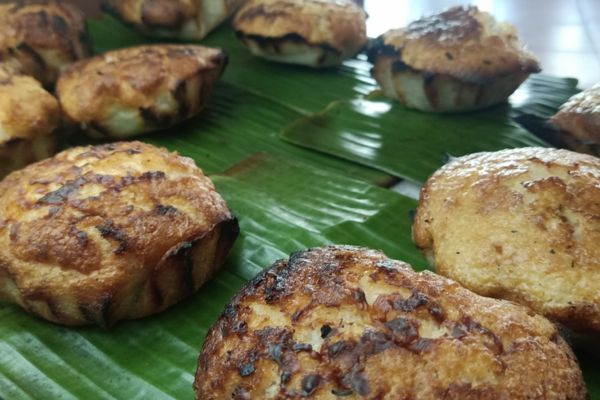 a round rice cake with brown crush on banana leaves